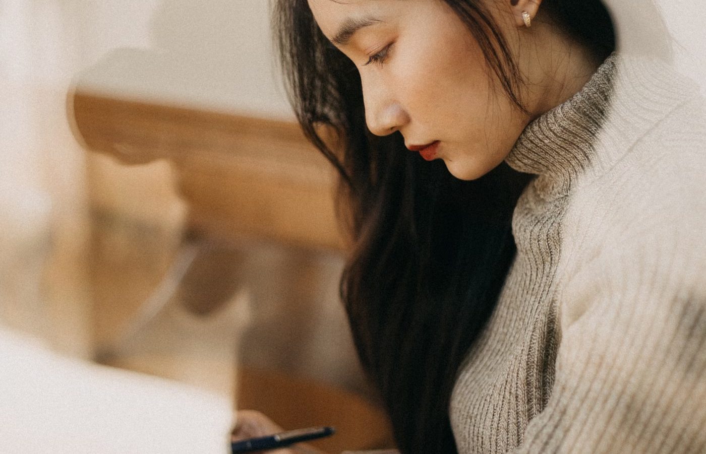 A person writing in a notebook by a window