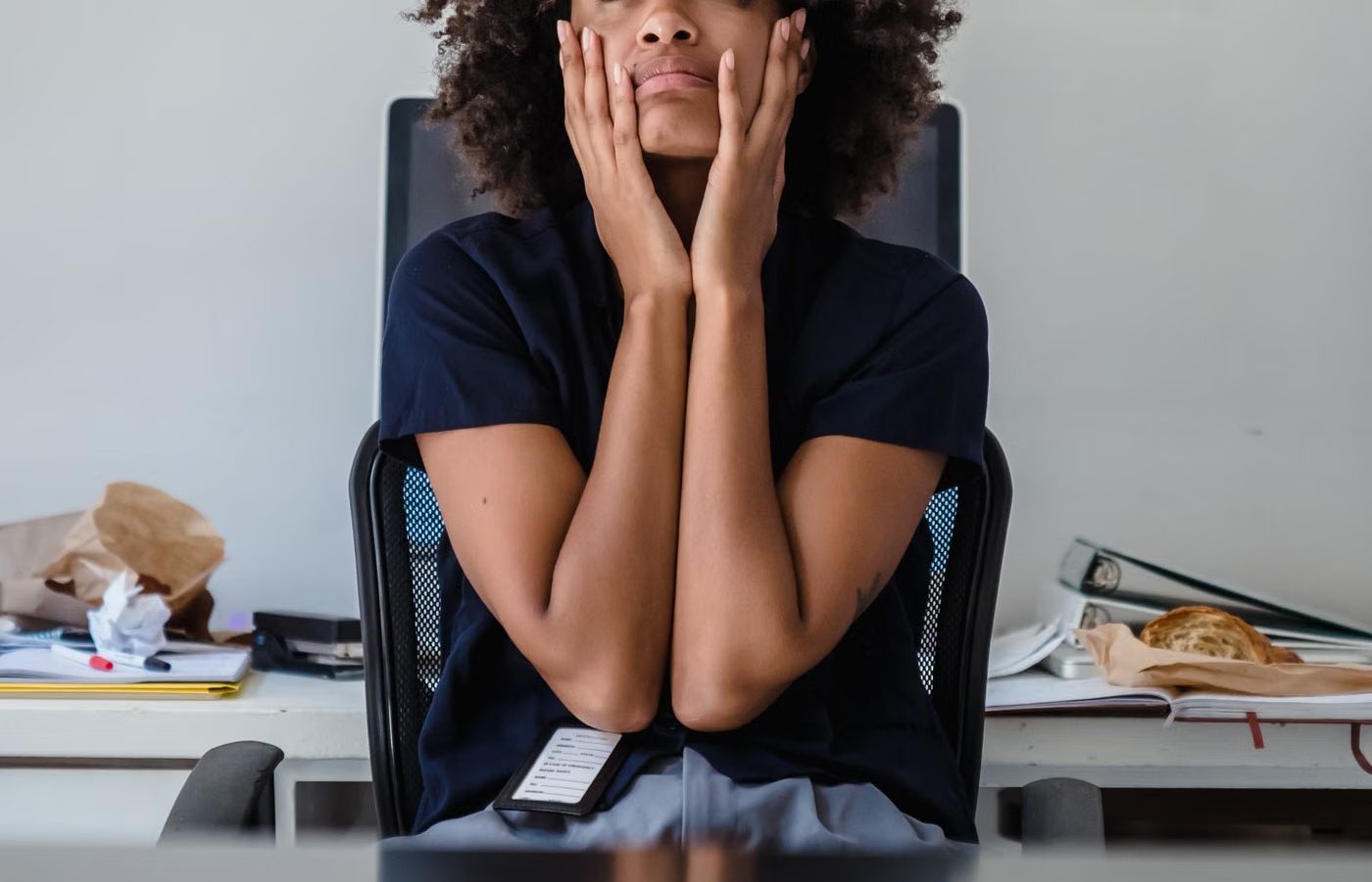 A woman at a desk with her hands to her face, lost in thought